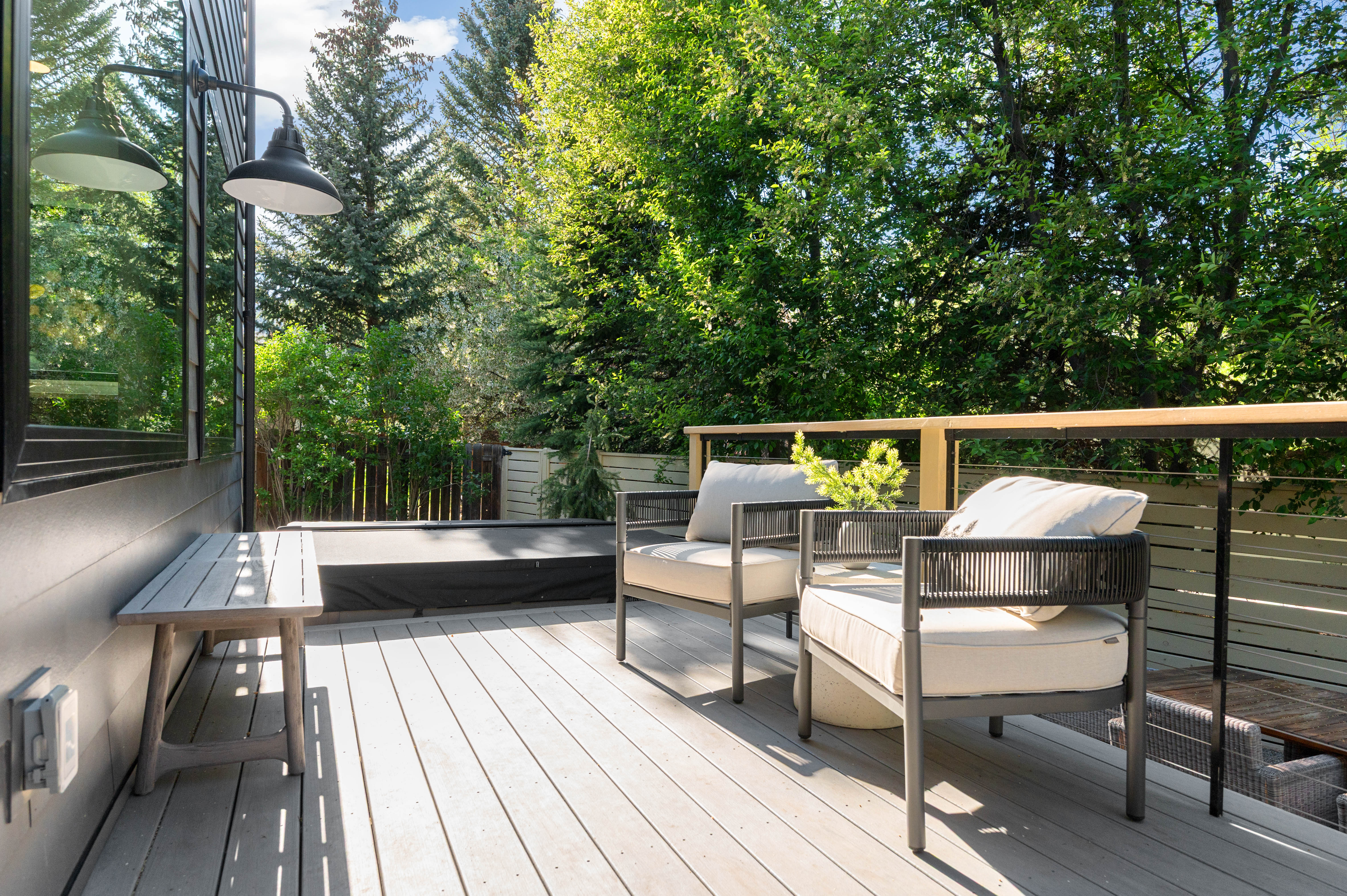 Outdoor deck featuring composite decking, wood-finish railing with metal balusters, and a built-in hot tub