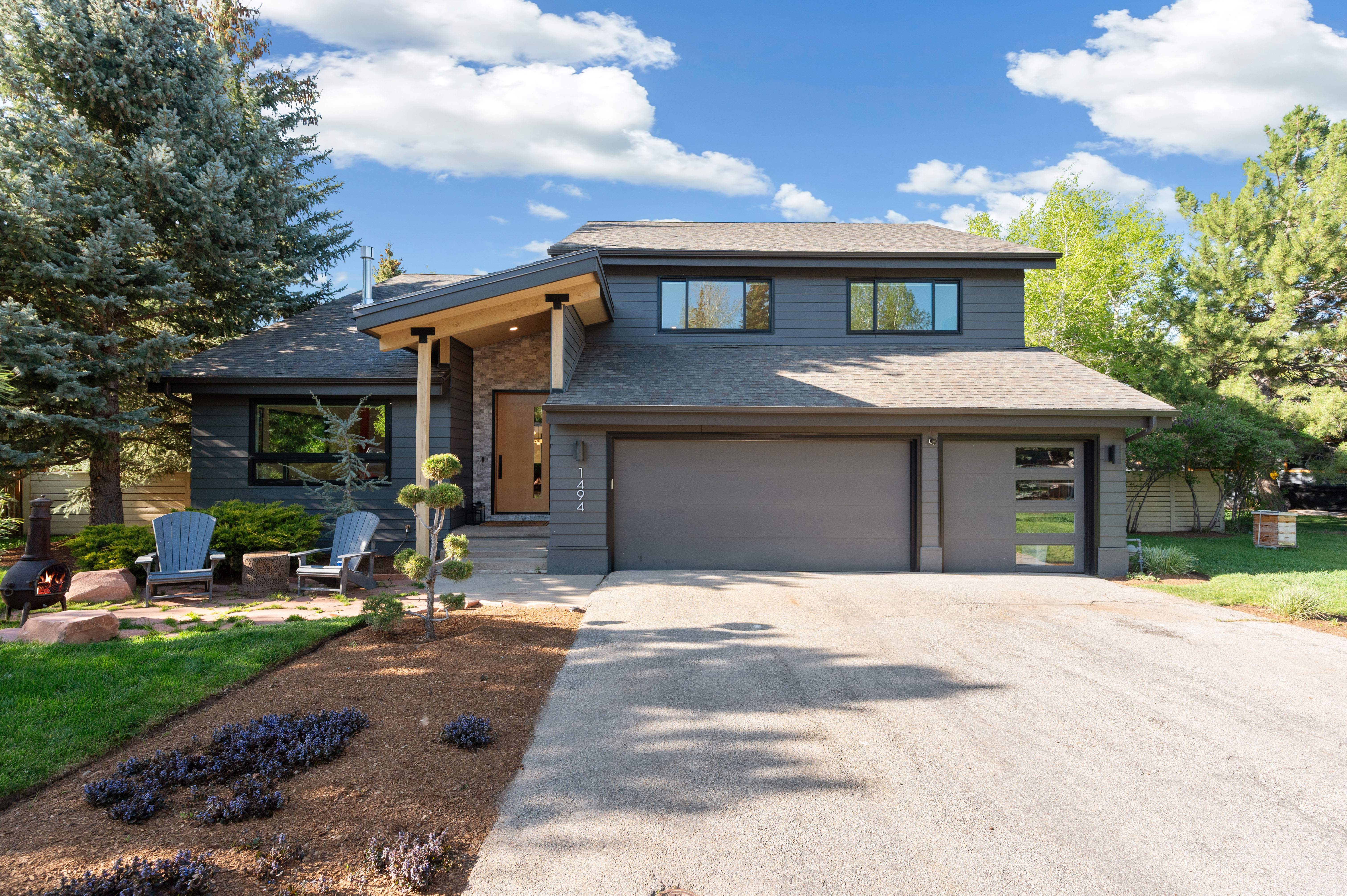 Contemporary dark gray siding with a contrasting light wood-paneled entry and stone accents