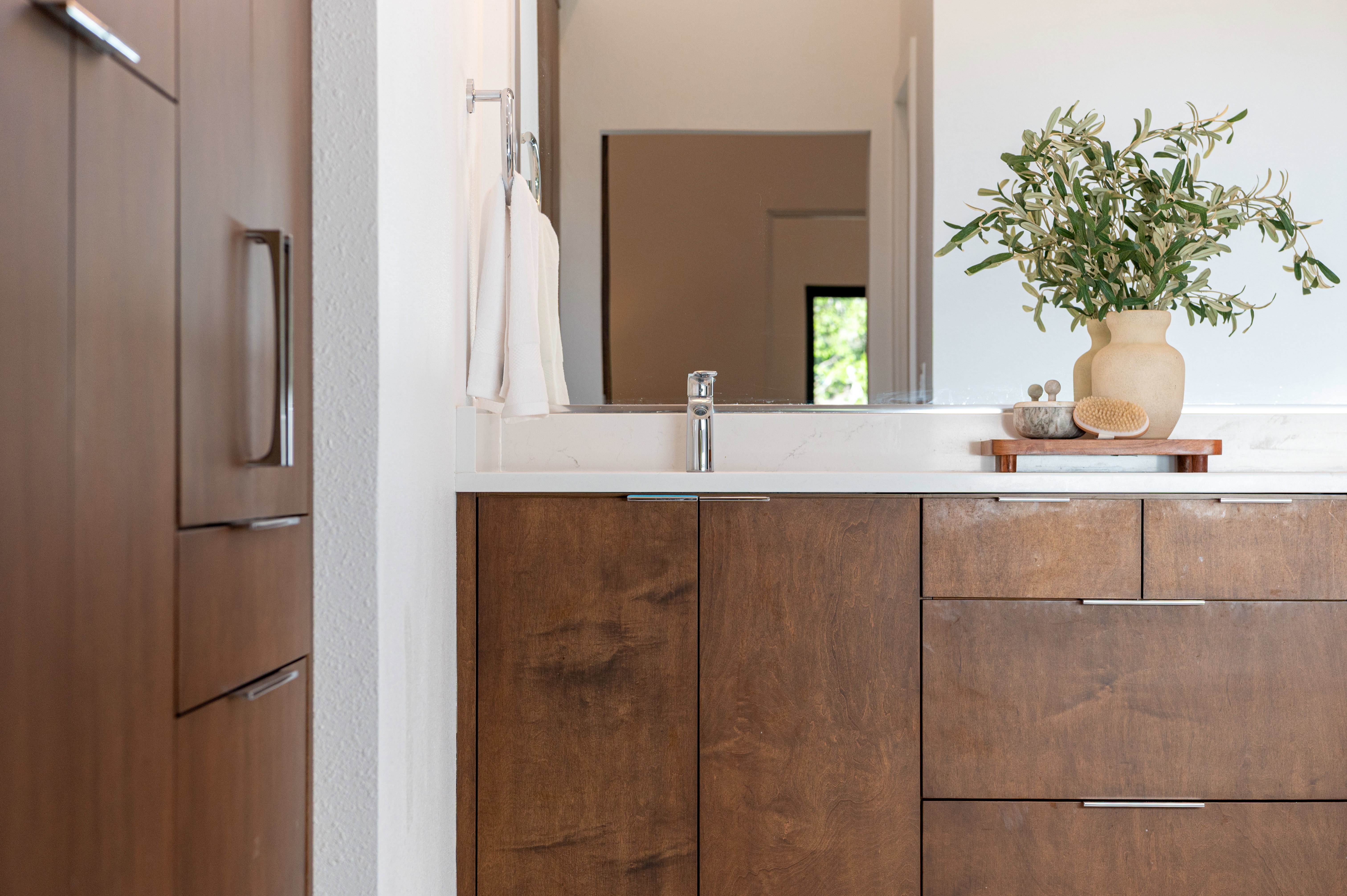 Vanity featuring rich wood-finish cabinetry, a light-toned countertop, and a sleek chrome faucet