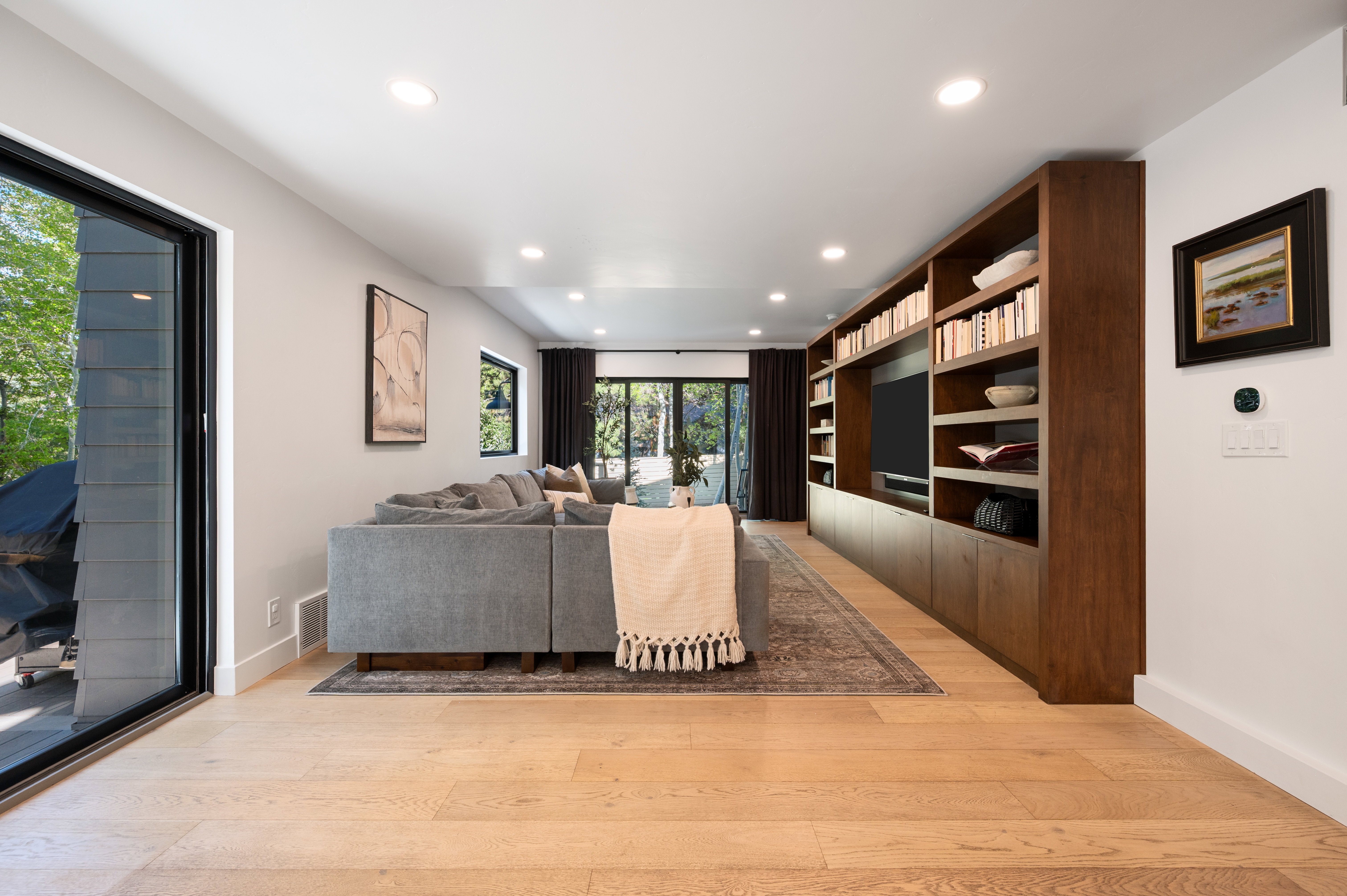 Spacious living area featuring light wood-finish flooring and recessed lighting
