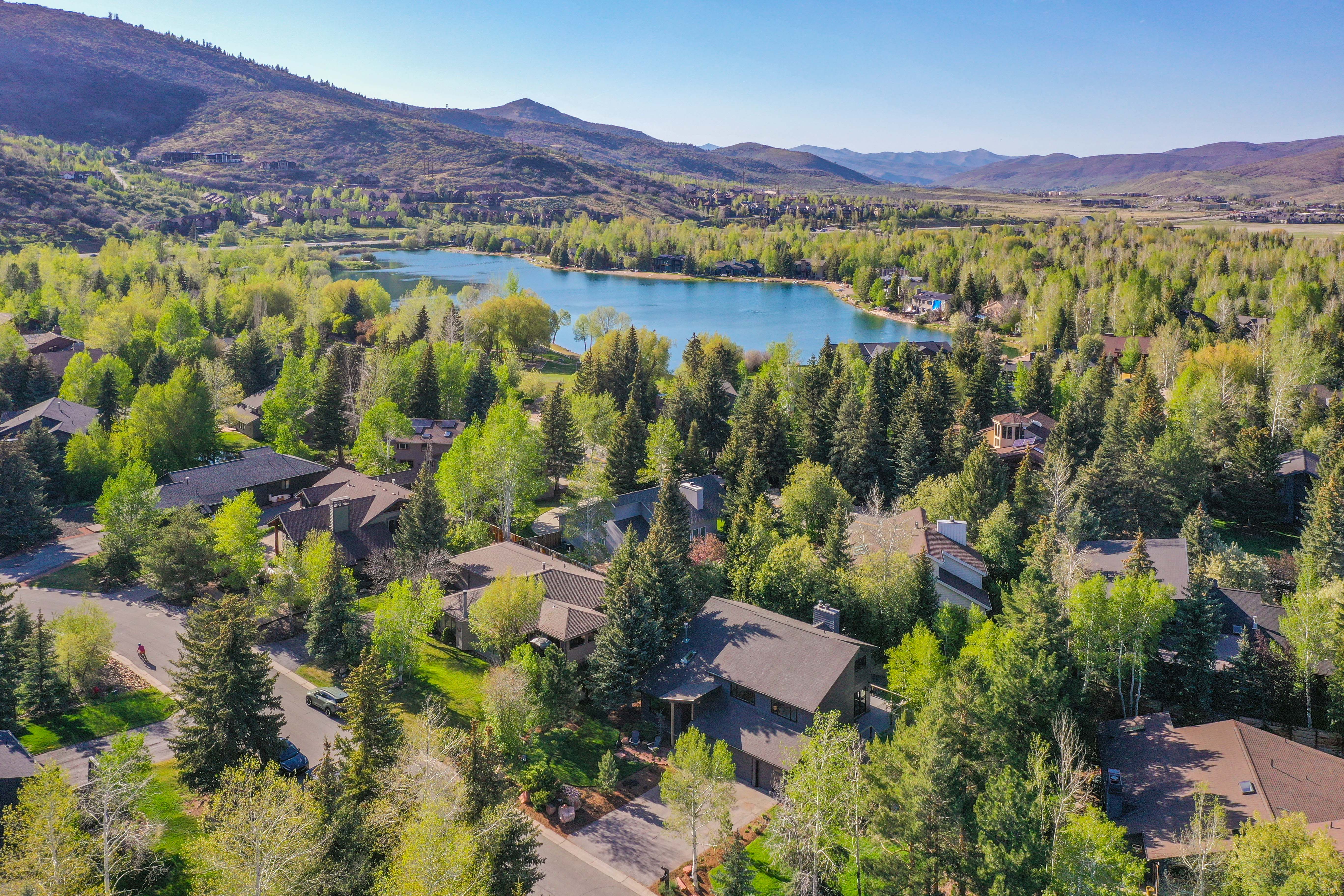 Aerial landscape featuring a vibrant blue lake surrounded by dense green trees and rolling hills