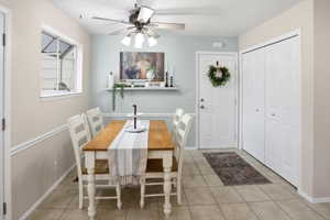 Dining area featuring a ceiling fan, a window, and tiled flooring