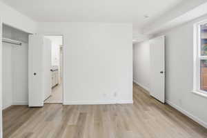 Spacious room featuring wood-finish flooring, white walls, and a window with exterior visibility