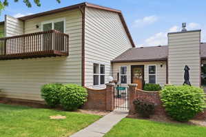 Exterior featuring light-colored horizontal siding, a private balcony with wood railing, and a gabled roof