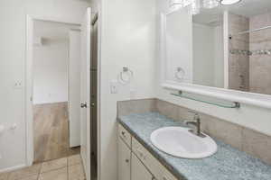 Bathroom vanity featuring an oval undermount sink with brushed nickel faucet, a speckled countertop, and white cabinetry