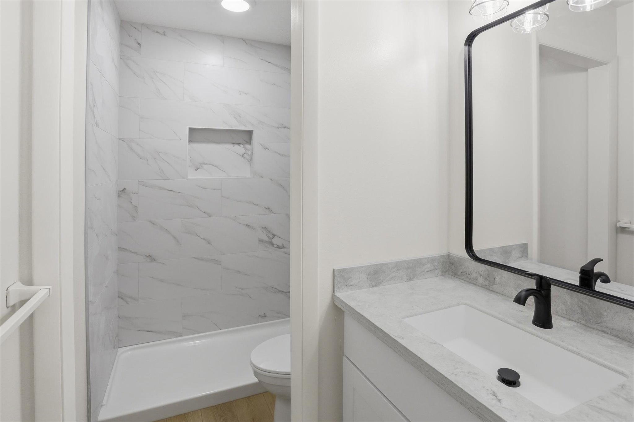 Bathroom featuring a vanity with an integrated sink, a dark-toned faucet, and a large framed mirror