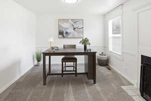 Carpeted room featuring white walls, chair rail molding, a window with blinds, and a built-in fireplace with a tiled hearth