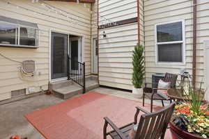 Concrete patio area featuring a sliding glass door with screen, a secondary entry door, and exterior wall siding