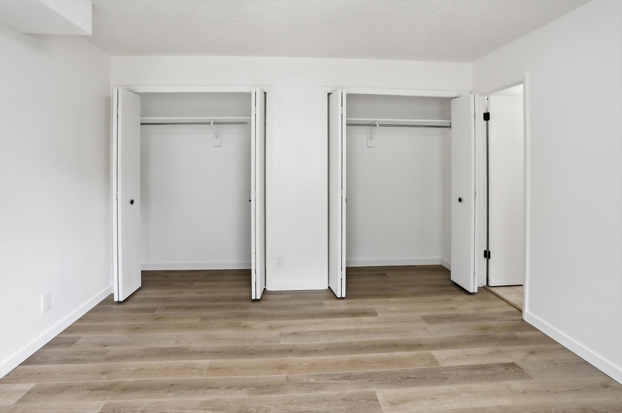 Room with wood-finish flooring, white walls, and white baseboards