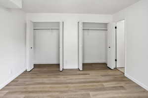 Room with wood-finish flooring, white walls, and white baseboards