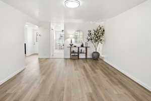 Spacious room featuring wood-finish flooring, white baseboards, and neutral wall paint