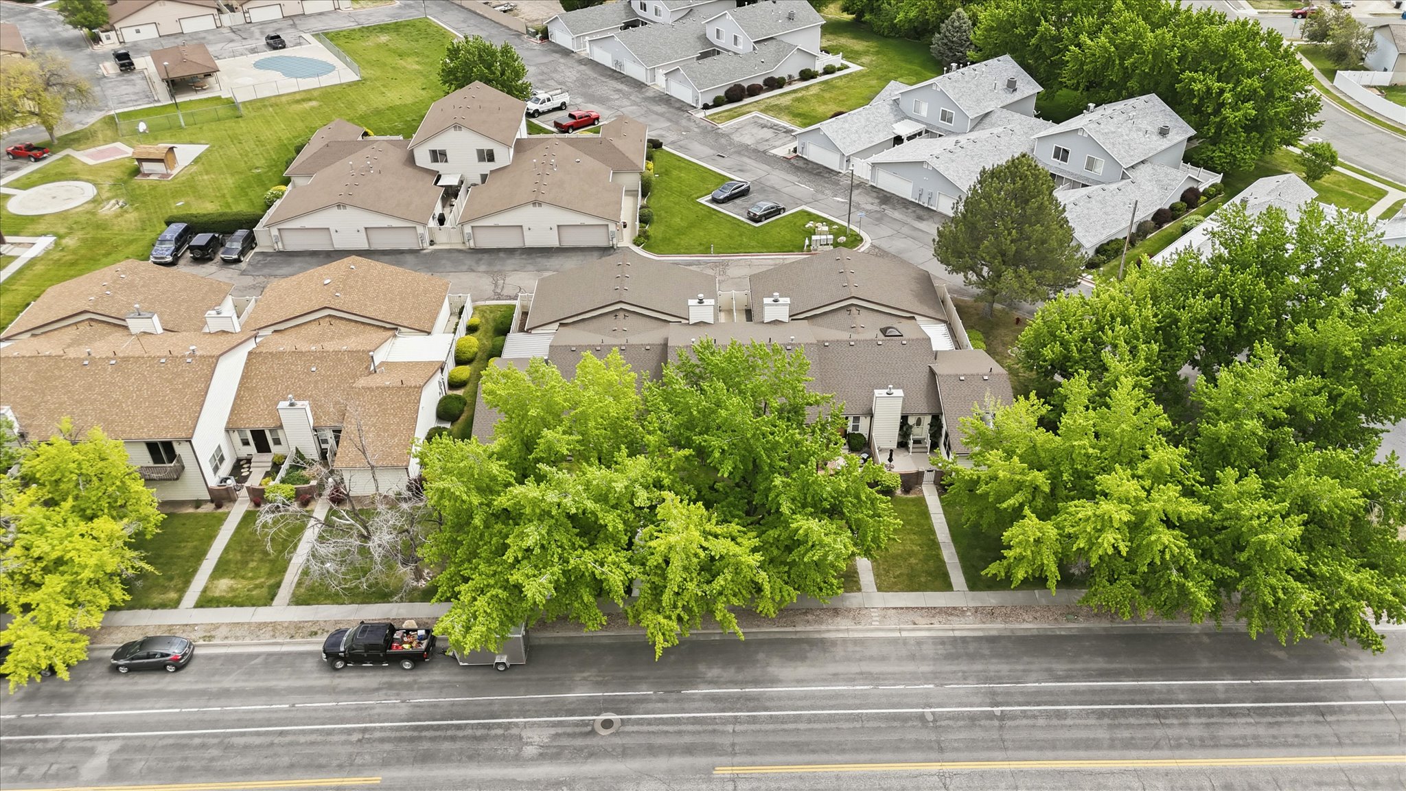 Aerial depiction of a residential community featuring townhomes with brown shingle roofing and light-colored facades