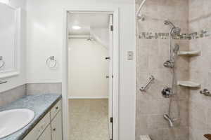 Bathroom featuring a tiled shower with mosaic accent band, multiple shower heads, and built-in shelving