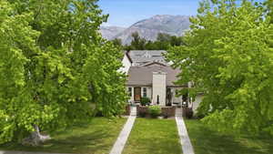 Exterior residence featuring a chimney, brown roof shingles, and light-colored siding