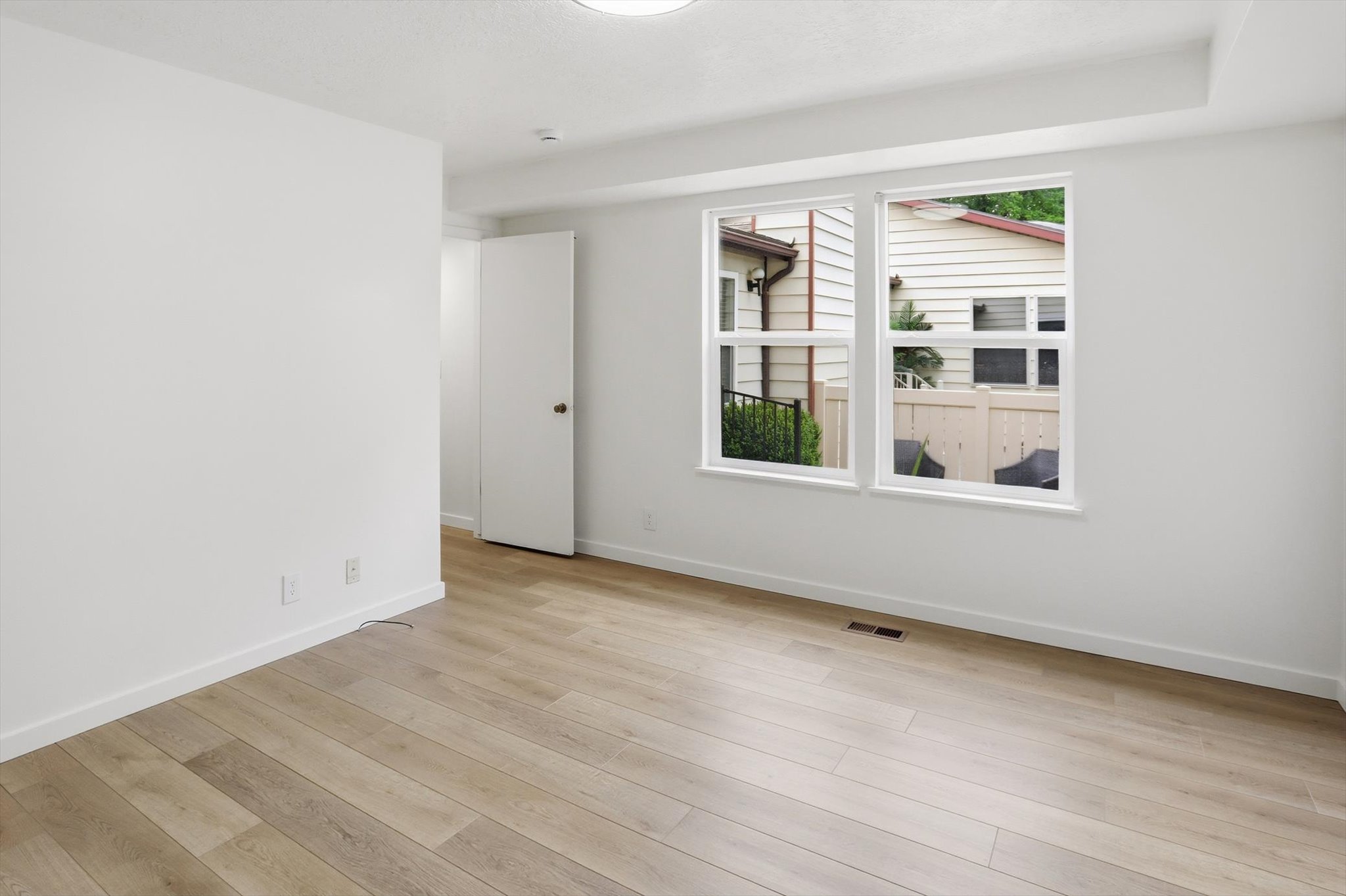 Bright room featuring wood-finish flooring, white walls, and a pair of windows