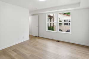 Bright room featuring wood-finish flooring, white walls, and a pair of windows