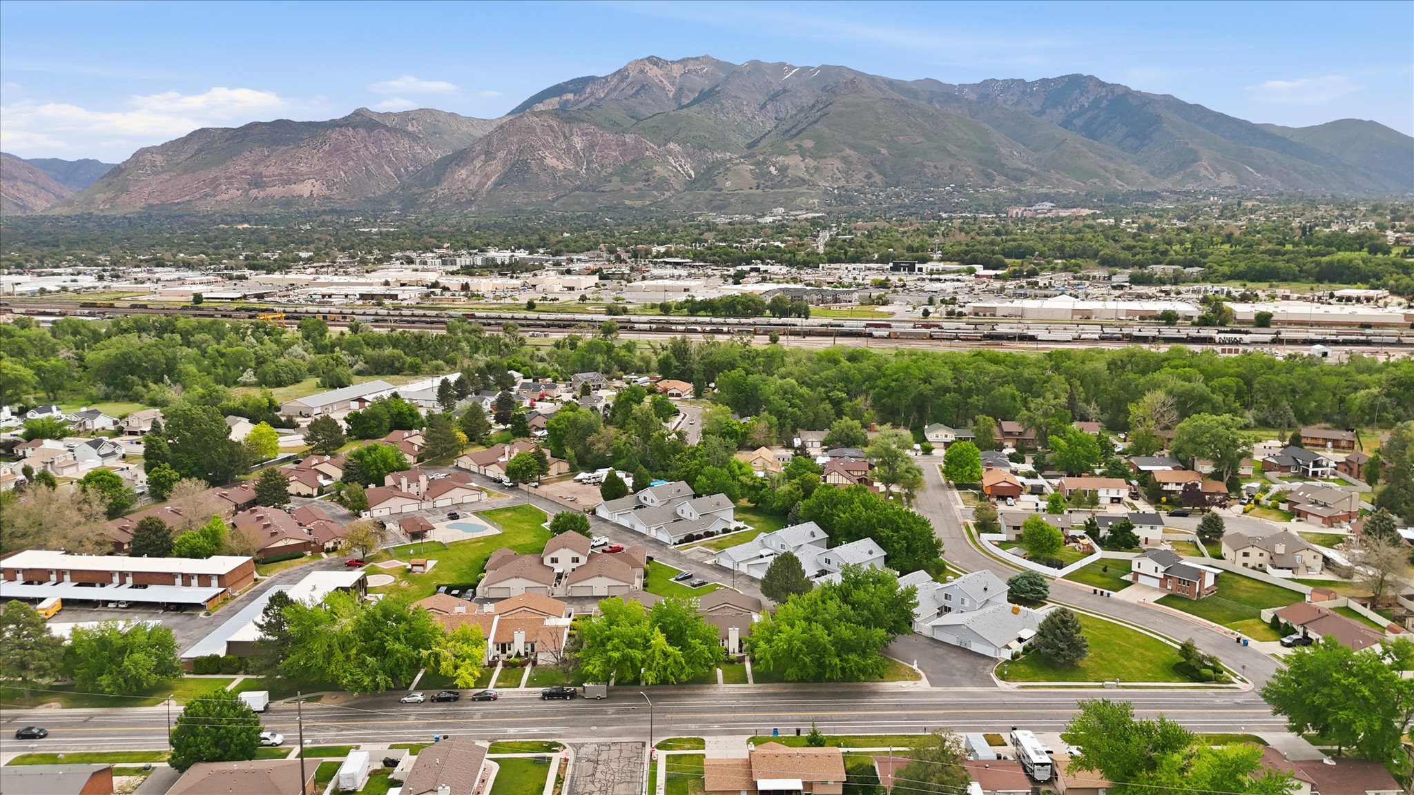 Aerial perspective showcasing a residential area with mature trees and mountain ranges in the background