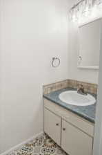 Bathroom vanity featuring a drop-in sink, gray countertop, mosaic tile backsplash, and decorative flooring