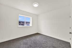 Room featuring a double-pane window, neutral white walls, dark gray carpeting, and white baseboards