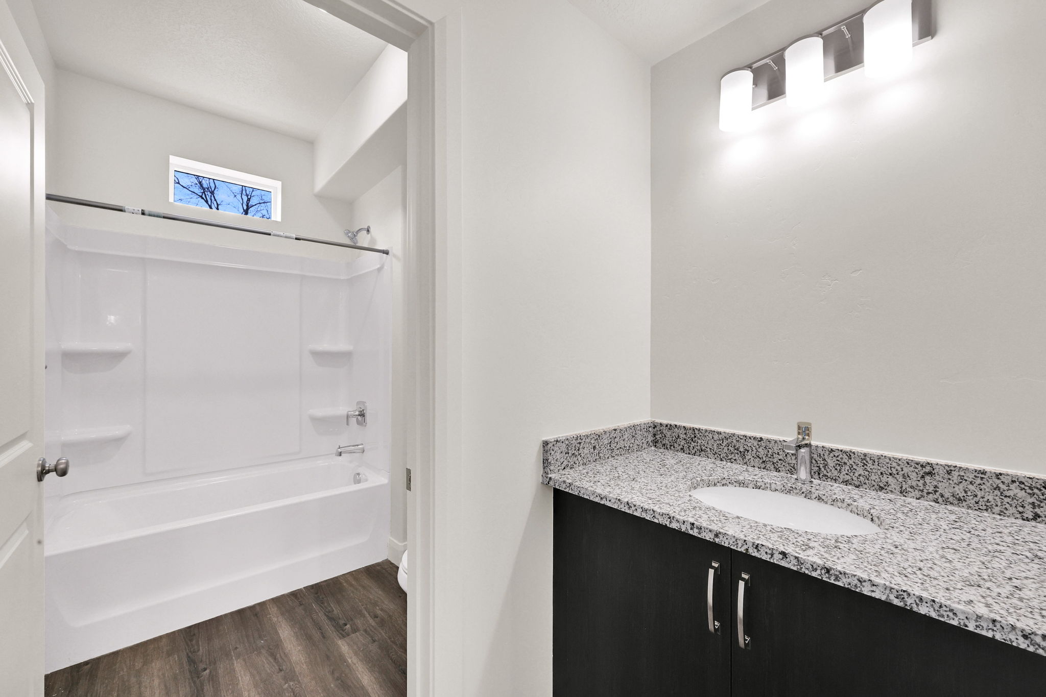 Bathroom featuring a dark wood-finish vanity with a light speckled countertop and undermount sink