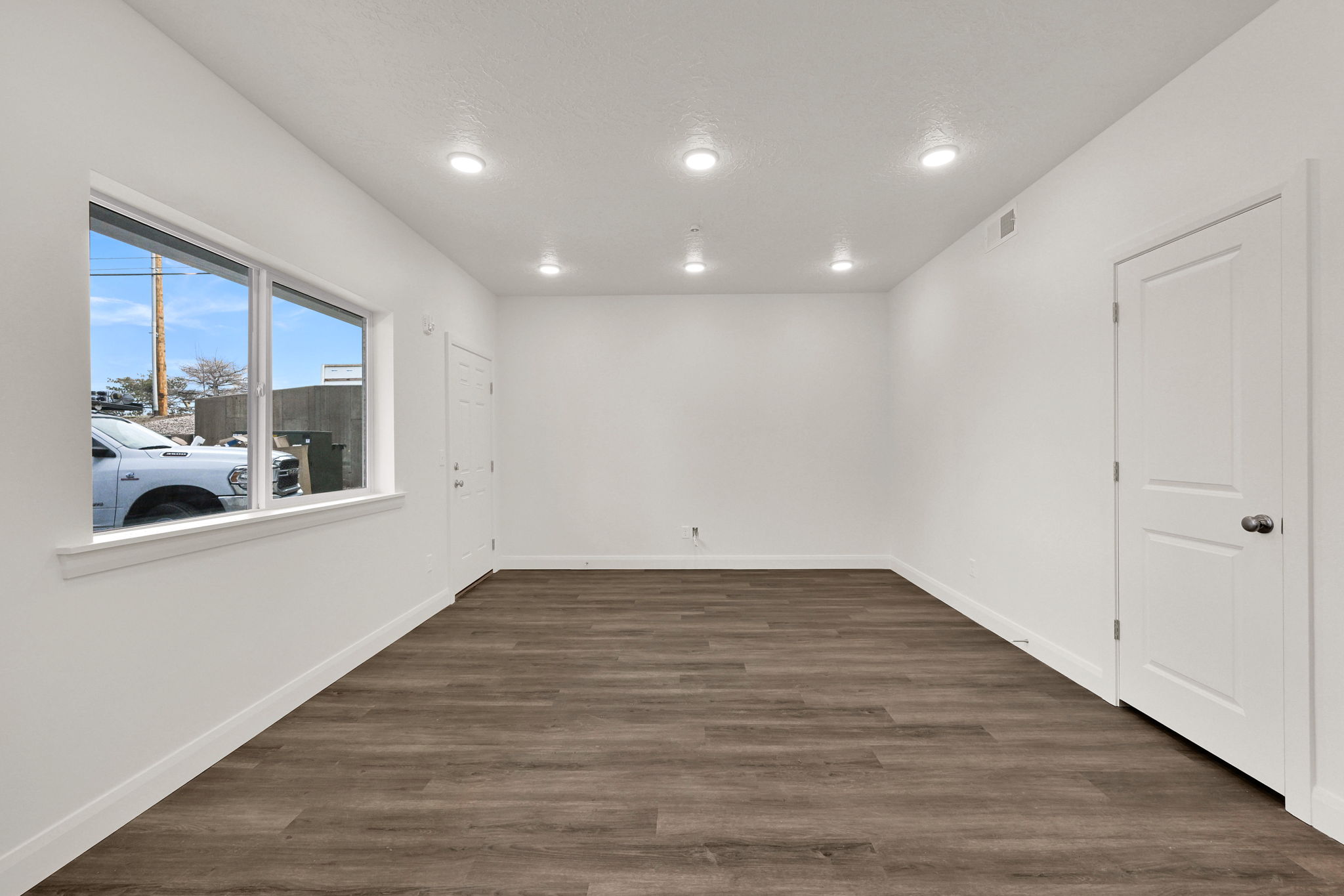 Spacious room featuring wood-finish flooring, recessed lighting, and a large window