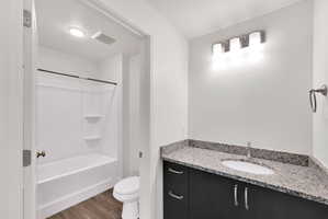 Modern bathroom featuring a dark wood-finish vanity with a light speckled countertop, under-mount sink, and chrome faucet