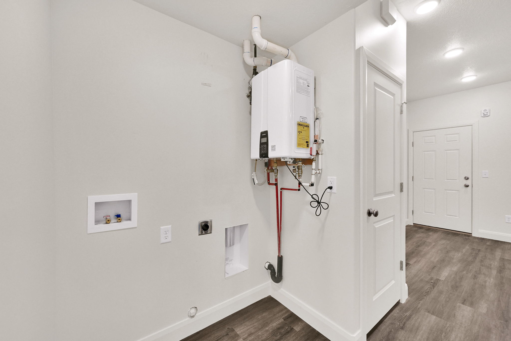 Dedicated utility area featuring a tankless water heater, laundry hookups, and wood-finish flooring