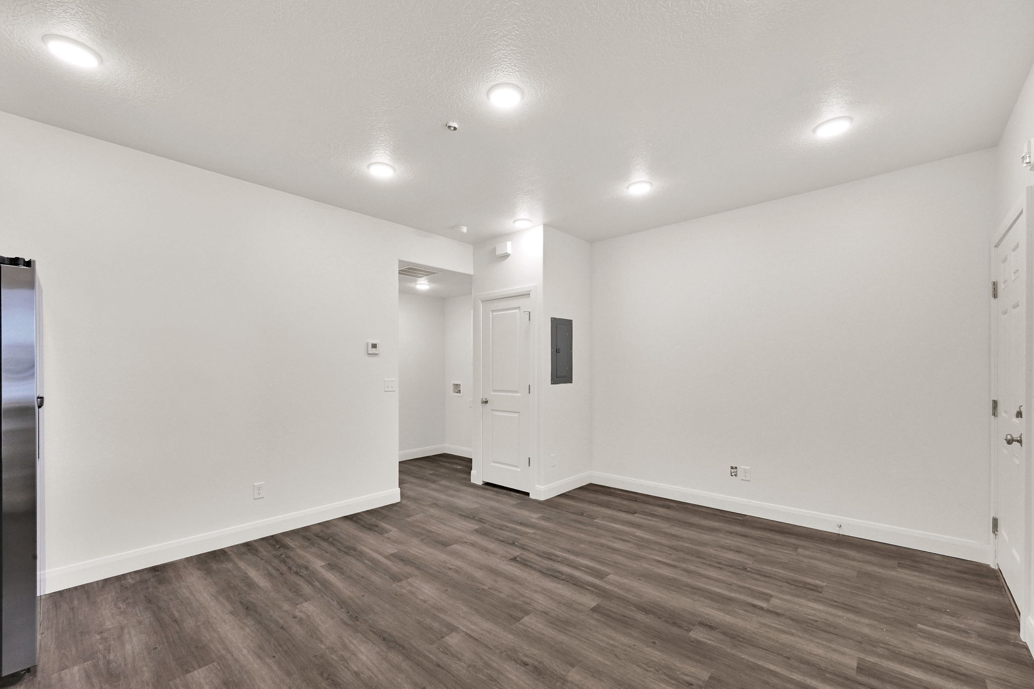 Open-concept living area with wood-finish flooring, white walls, and recessed lighting