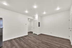 Open-concept living area with wood-finish flooring, white walls, and recessed lighting
