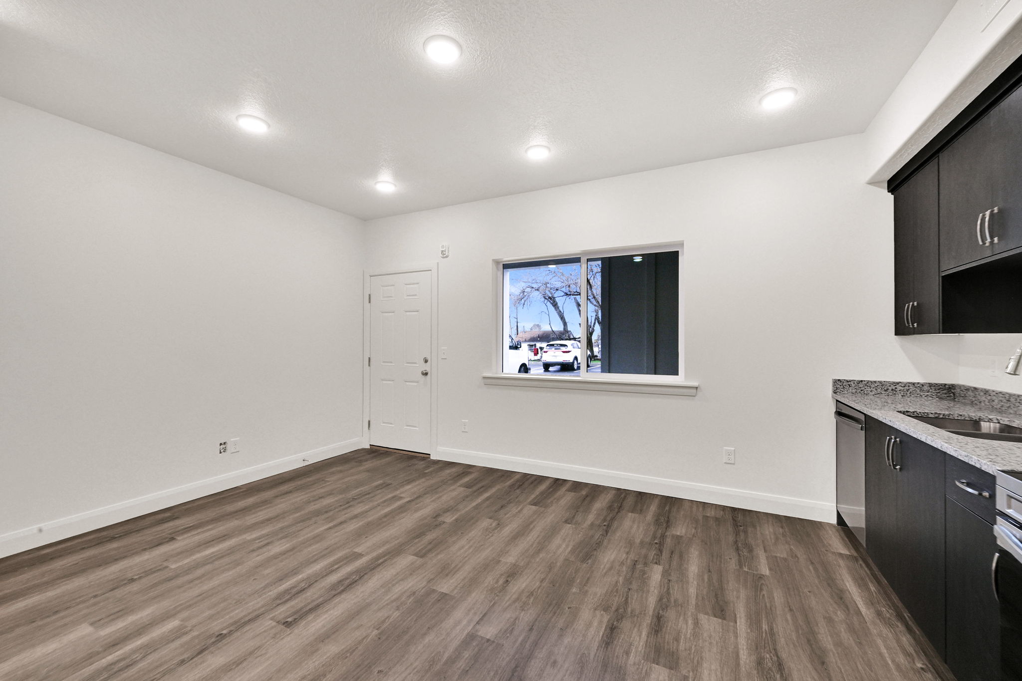 Open-concept living space featuring wood-finish flooring, recessed lighting, and white walls