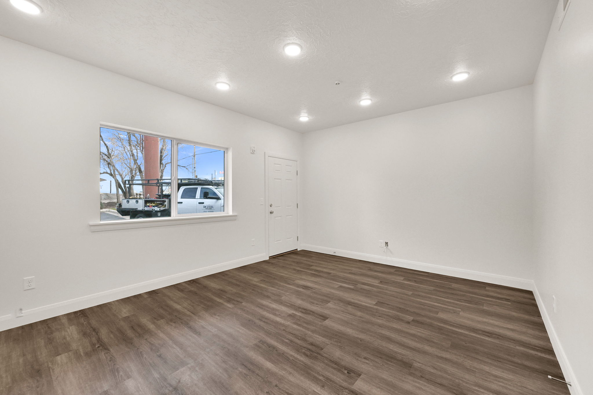 Open-concept room featuring wood-finish flooring, white baseboards, and neutral wall paint