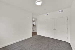 Wall-to-wall carpeting in a neutral tone, white baseboards, and a pair of white doors with silver knobs