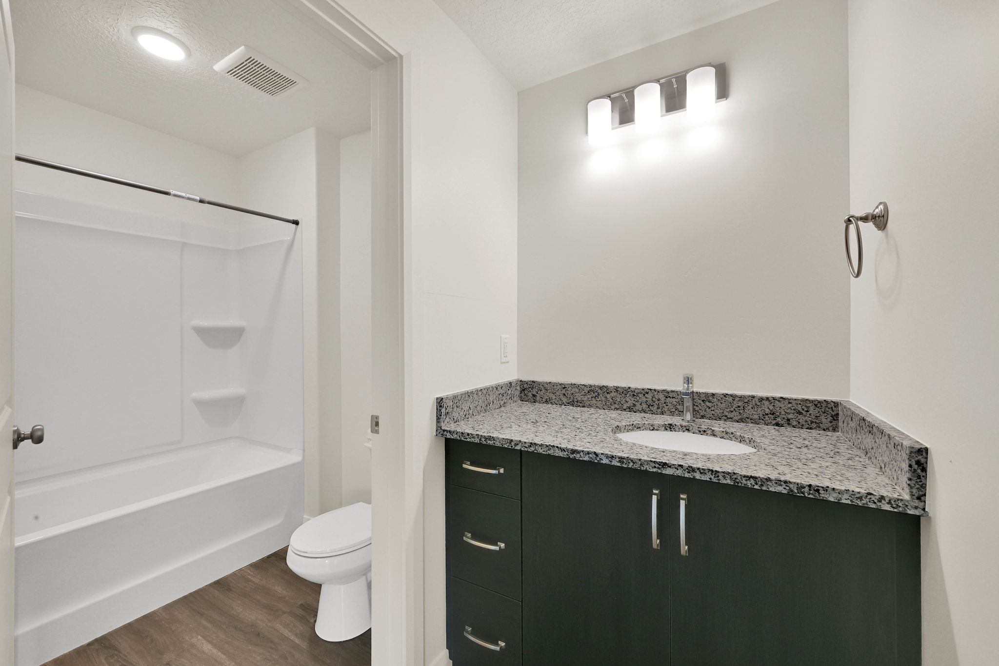 Bathroom featuring a dark wood-finish vanity with a granite-style countertop, undermount sink, and brushed nickel hardware