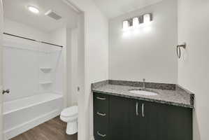 Bathroom featuring a dark wood-finish vanity with a granite-style countertop, undermount sink, and brushed nickel hardware