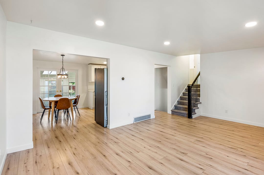 Open-concept living area with wood-finish flooring, recessed lighting, and white baseboards