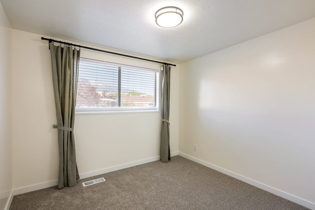 Room featuring a window with horizontal blinds, neutral wall paint, and gray carpet flooring