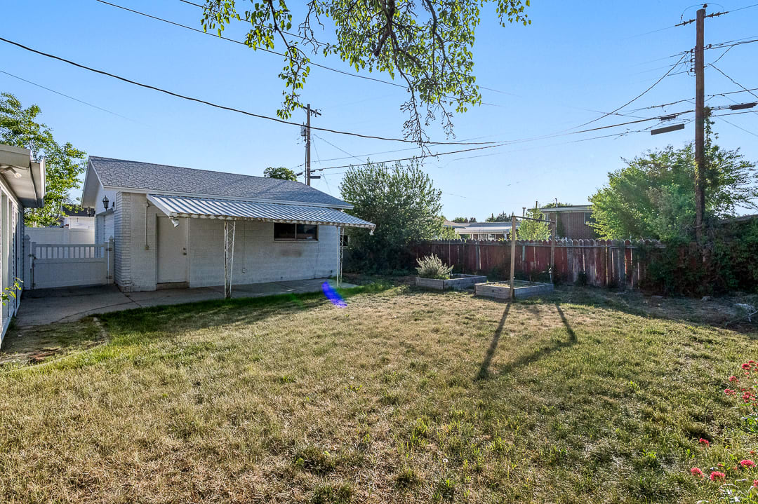 Expansive rear yard featuring a manicured lawn, concrete patio, and a white brick exterior