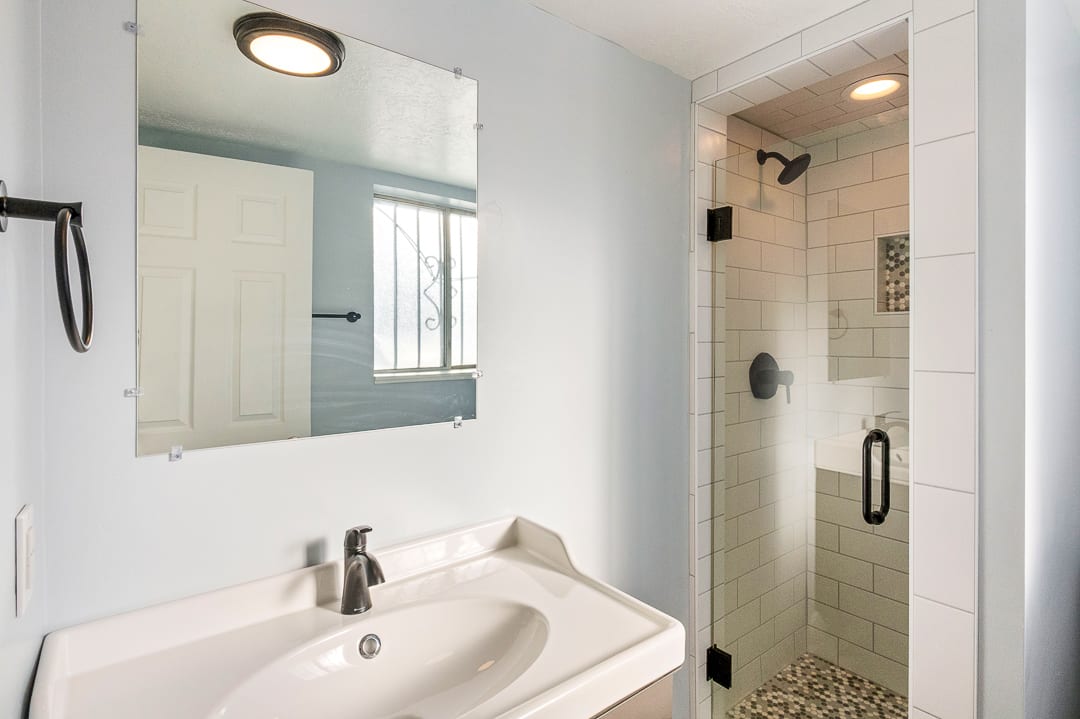 Modern bathroom featuring a glass-enclosed shower with subway tile surround and pebble-style flooring