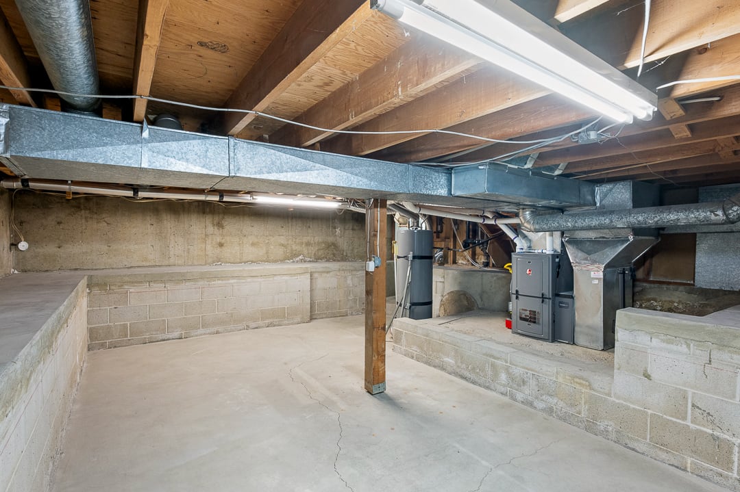 Unfinished lower level featuring exposed wood joists, concrete flooring, and concrete block walls