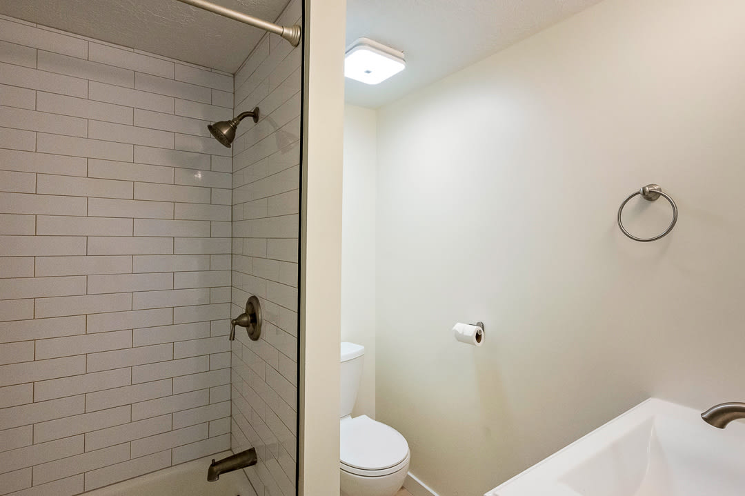 Bathroom featuring a tiled shower with bronze fixtures, a glass shower partition, and a white toilet