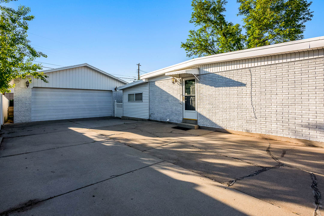 Concrete driveway providing access to a two-car garage with a white sectional door, and a separate entry door