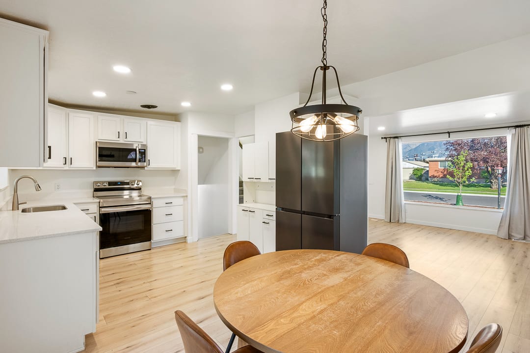 Contemporary kitchen featuring white cabinetry, light-toned countertops, stainless steel appliances, and wood-finish flooring