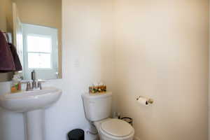 Pedestal sink with chrome-finish faucet, wall-mounted mirror, and a white toilet