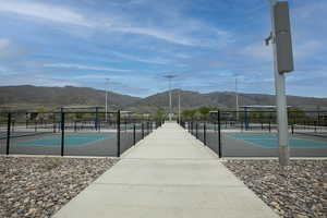 Outdoor sports courts featuring chain-link fencing, high-mast lighting, and mountain scenery