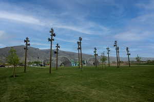 Expansive green space featuring a manicured lawn, distant mountain backdrop, and scattered decorative tree-like structures