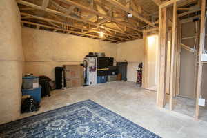 Unfinished basement space featuring exposed wood framing, concrete flooring, and partial wall insulation