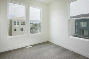 Light-filled room featuring five large windows, neutral carpeting, white walls, and white baseboards