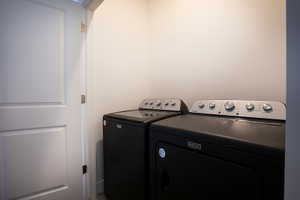 Dedicated laundry area featuring a white paneled door and modern black appliances