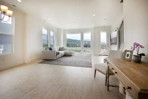 Bright living space with light wood-finish flooring, recessed lighting, and expansive windows