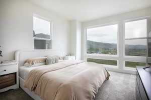 Bright bedroom featuring multiple windows, including large picture windows showcasing a mountainous landscape